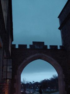 After the storm: dark sky and stone arch between buildings